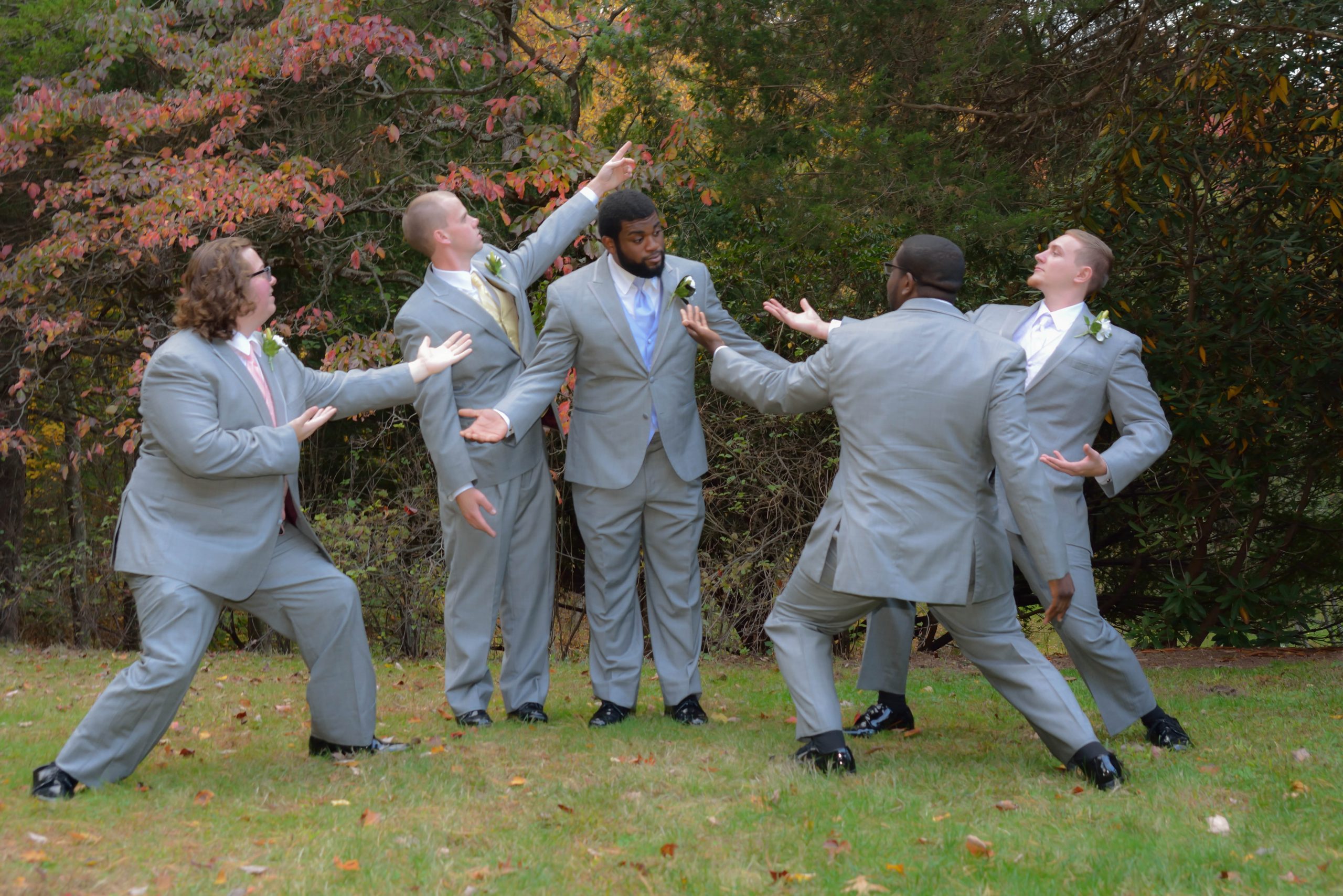 Groom surrounded by his groomsmen who are all doing funny poses