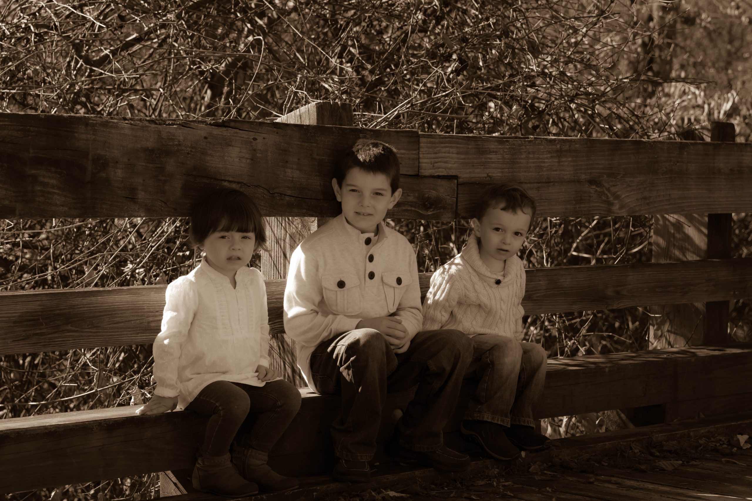 3 children sitting on a ledge looking at the camera with a serious face