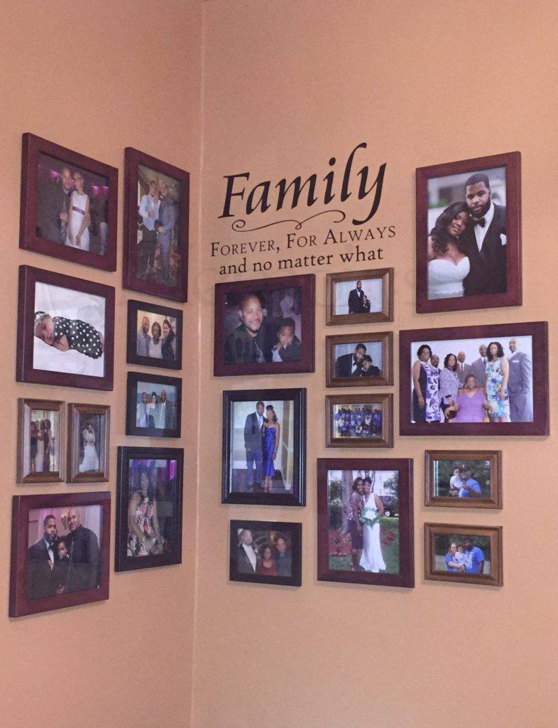 Various sized pictures in frames on a wall with a quote about family above it