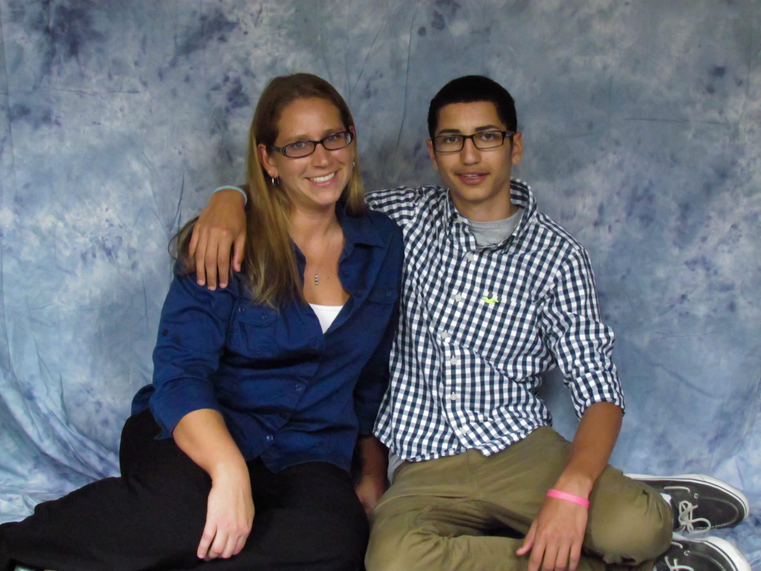 Mother sitting on the floor with her son who has his arm around her shoulder